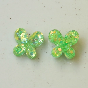 Vista macro de dijes de mariposa en resina verde con lentejuelas brillantes para joyas DIY