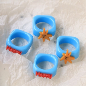 Set of four blue resin rings featuring orange star smiley faces and red Happy charms