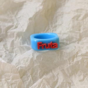 Macro shot of Sky Blue Resin Square Ring with Red 3D Fruta Text in Y2K Pop Art style