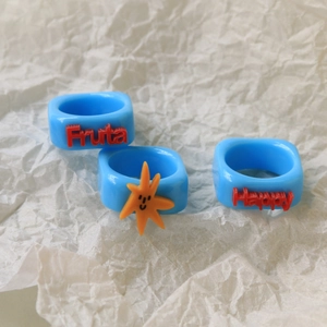 Close-up of blue resin rings featuring red Fruta Happy text and orange starfish details