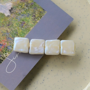 Vue détaillée d'une barrette en perles carrées crème sur une assiette en céramique