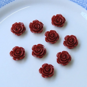 Detalle de nueve rosas de resina roja para la creación de joyas DIY sobre blanco