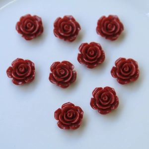 Vista plana de nueve dijes de rosas de resina roja para joyería y accesorios
