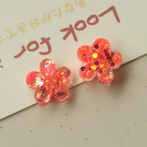 Macro shot of resin flower charms with orange and gold sequins for DIY jewelry making