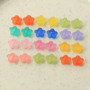 Top view of translucent matte resin flower charms in various candy colors on a tray