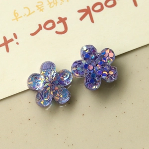 Macro shot of purple resin flower charms with colorful sequins for DIY accessories