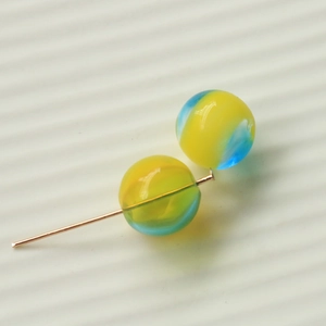 Macro shot of 16mm gradient glass beads on a gold pin for DIY jewelry making accessories
