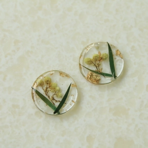 Vue macro de breloques rondes en résine avec feuilles d'or et fleurs jaunes séchées