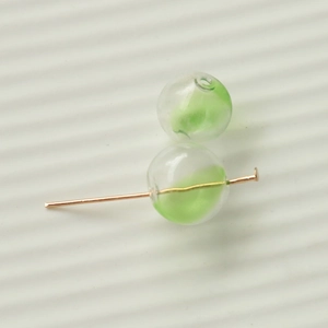 Green gradient stripe 16mm glass beads with golden metal pin on white texture background