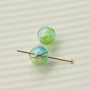 Detailed macro view of 16mm gradient stripe glass beads with golden T-pin for DIY jewelry