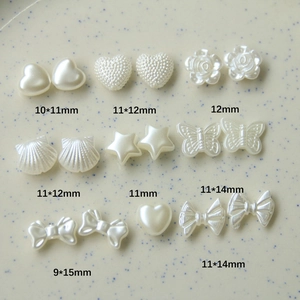 Dettaglio di ciondoli in finta perla bianca a forma di cuore, conchiglia e farfalla per DIY
