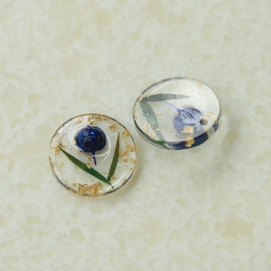 Vue détaillée de breloques en résine avec fleurs séchées bleues et feuilles d'or