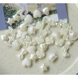 Assortimento di ciondoli in perla sintetica con rose e conchiglie su vassoio ceramico