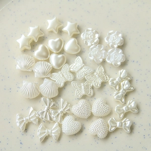 Dettagli di ciondoli in resina bianco perlato tra cui rose conchiglie e stelle