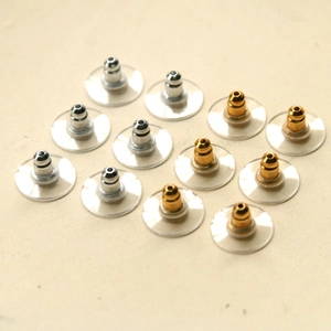 Macro detail of 12 gold and silver earring backs with transparent stabilizer discs