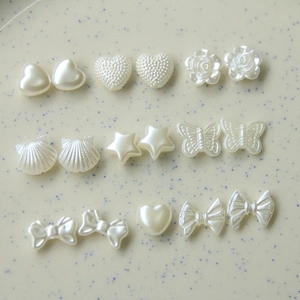 Vista macro di ciondoli per unghie in perle bianco crema in varie forme su vassoio ceramico