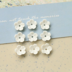 Vue détaillée de fleurs en résine blanche pour bijoux DIY avec cinq pétales et trou central