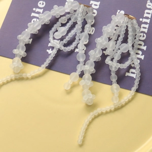 Elegante lange kwastjes oorbellen van matglas met witte kralen en gouden details