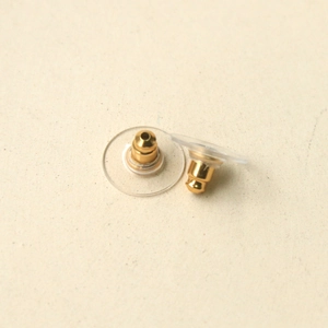 Close-up of golden metal core ear nuts with transparent plastic disc pads for DIY jewelry
