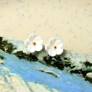 Photo macro de clous d'oreilles fleurs blanches et perles dorées sur cartes