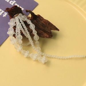 Detail van matte witte kralen met een bronzen ring op donker decoratief hout