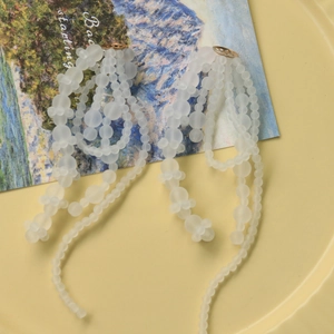 Lange oorbellen van matte doorschijnende witte kralen met een elegante gouden ketting