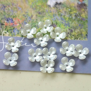 Macro shot of white pearlescent four-petal resin flower beads for DIY jewelry making