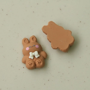 Detailed view of cute brown resin bunny charms with white bows for DIY jewelry and crafts