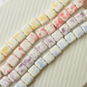 Close-up of square ceramic beads with colorful splash ink marble texture for DIY jewelry