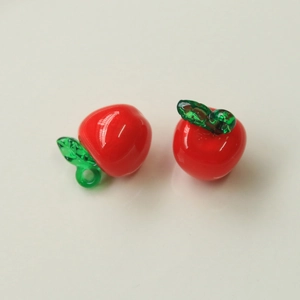 Close-up of glass apple beads with green leaves for DIY jewelry making