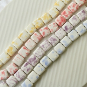 Close-up of four-color square ceramic beads with artistic splatter pattern for DIY jewelry