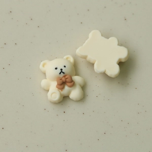 Detailed view of cream bear resin charms with brown bows for DIY crafts and accessories