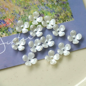 Macro shot of white pearlescent 5-petal flower beads for DIY jewelry making