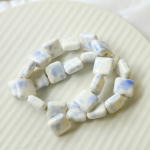 Close-up of square ceramic beads with blue and white ink cow patterns for DIY jewelry