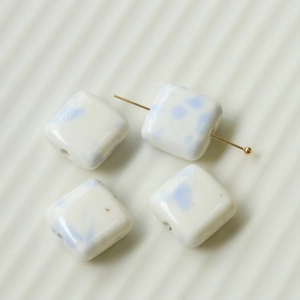 Close-up of square ceramic beads with light blue ink splash pattern and through-hole