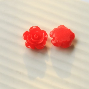 Macro view of red resin rose flower charms showing front petal detail and flat back base