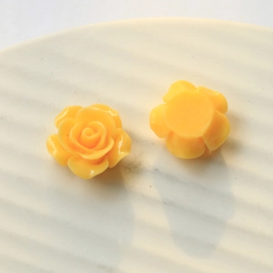 Macro view of bright yellow resin rose flower charms for DIY crafts and hair accessories