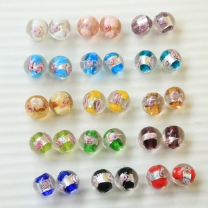 Detail von handgefertigten Glasperlen mit Blumenmustern und Silberfolie für DIY-Schmuck