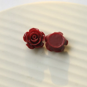 Detailed view of resin rose charms with deep red petals and a flat back for DIY crafts