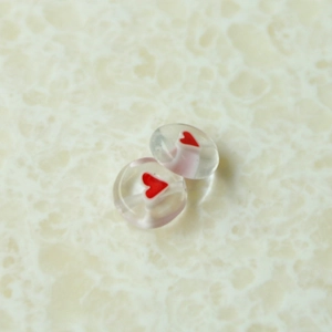 Nahaufnahme klarer herzförmiger Glasperlen für DIY-Schmuck auf Marmorgrund