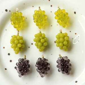 Dettaglio macro di ciondoli in resina a forma di uva in vari colori con anelli dorati