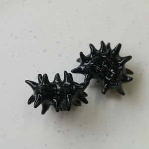 Detail view of two black spiky massage balls for hand therapy on a textured background