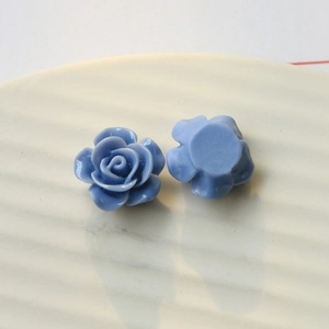 Macro view of light blue resin rose flower charms for DIY jewelry and phone case crafts