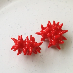 Macro shot of two red spiky 3D resin spheres with detailed urchin-like thorn texture