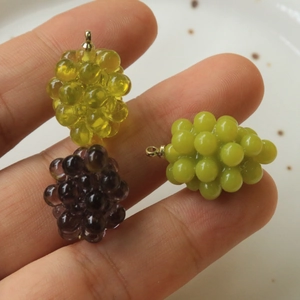 Dettaglio dei ciondoli in resina a forma di uva nei colori viola, giallo e verde