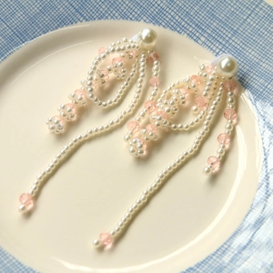 French vintage tassel pearl crystal bow earrings with white and pink beads in a ceramic tray