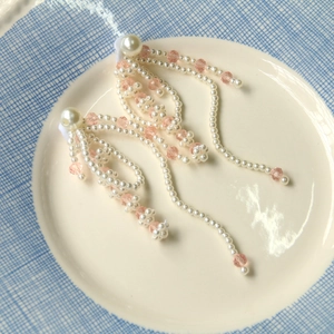 Detail of beaded tassel earrings with white pearls and pink crystals in a ceramic dish