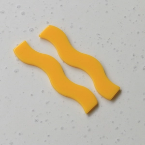 Détail de breloques en acrylique jaune ondulé pour la création de bijoux artisanaux