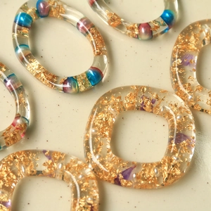 Dettaglio di anelli in resina con foglia d'oro e perle per gioielli fai-da-te e accessori