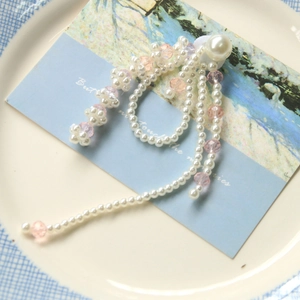 Vintage French bow accessory with pearl tassels and pink crystal beads on a blue ceramic plate